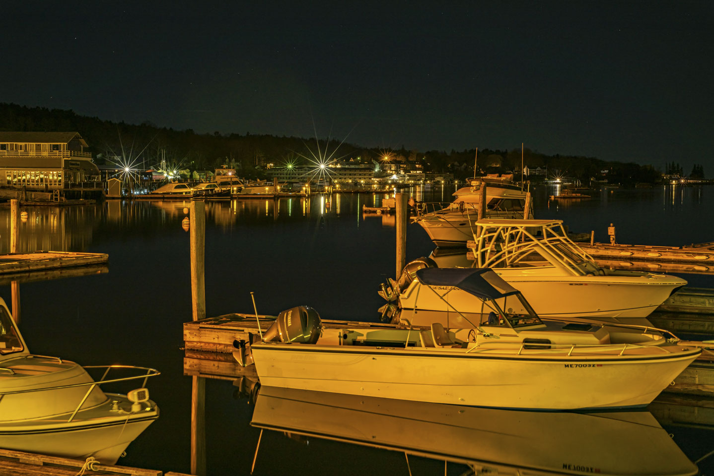 boats in dock with the lights of Boothbay Harbor sparkling in the background
