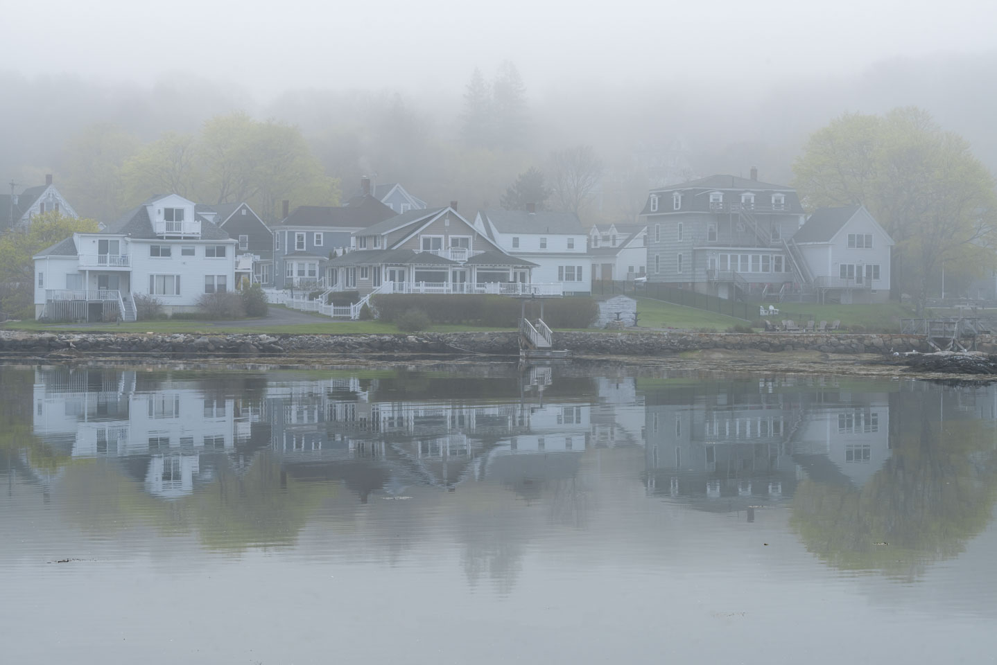 Houses reflected in water and surrounded by fog