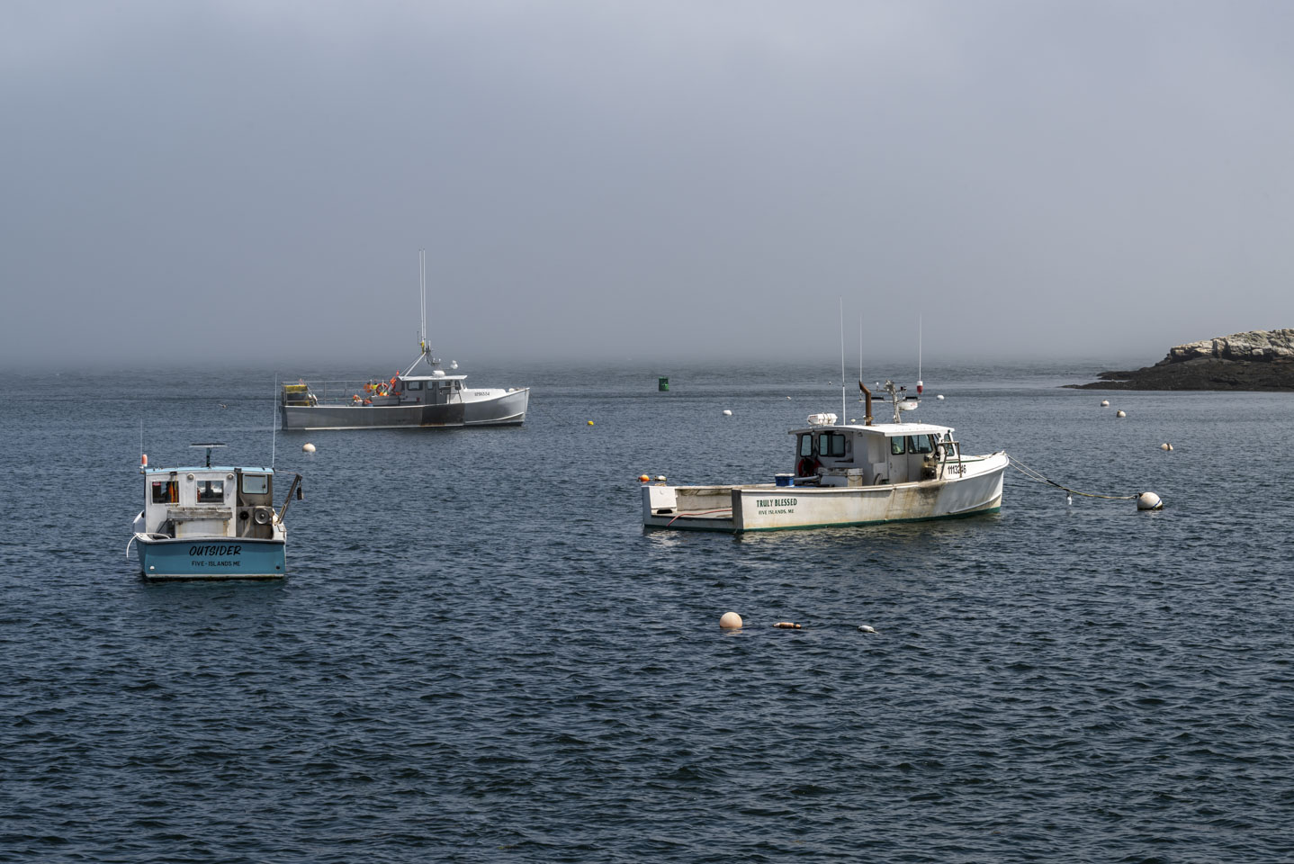 Five Islands harbor with 3 boats in front of a wall of fog