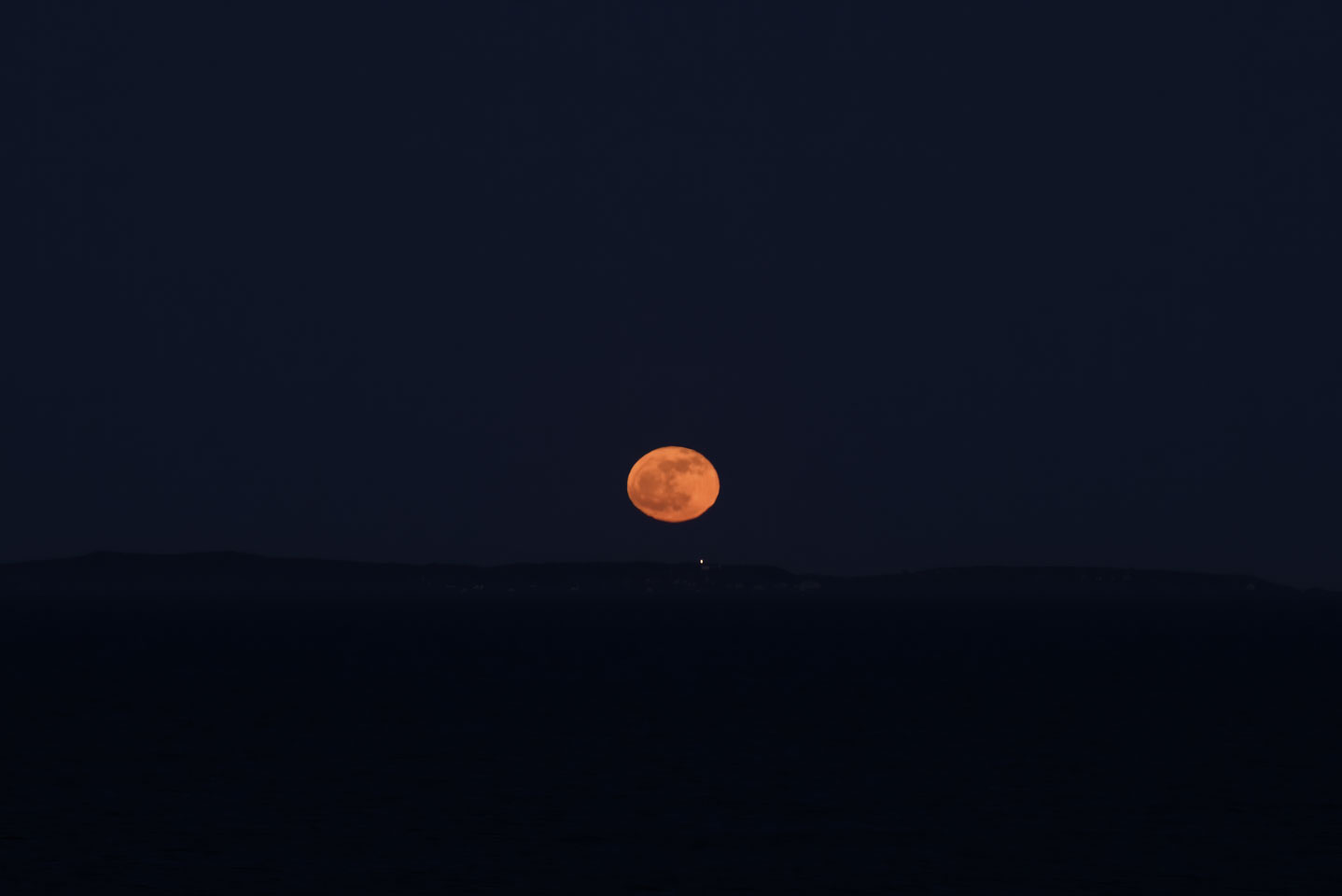 moon over Monhegan Island with the island lighthouse light visible