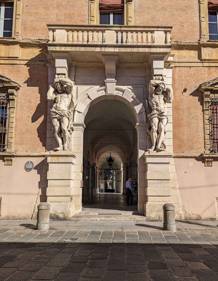 A large stone entrance with a male figure carved in stone positioned on each side of the entrance.