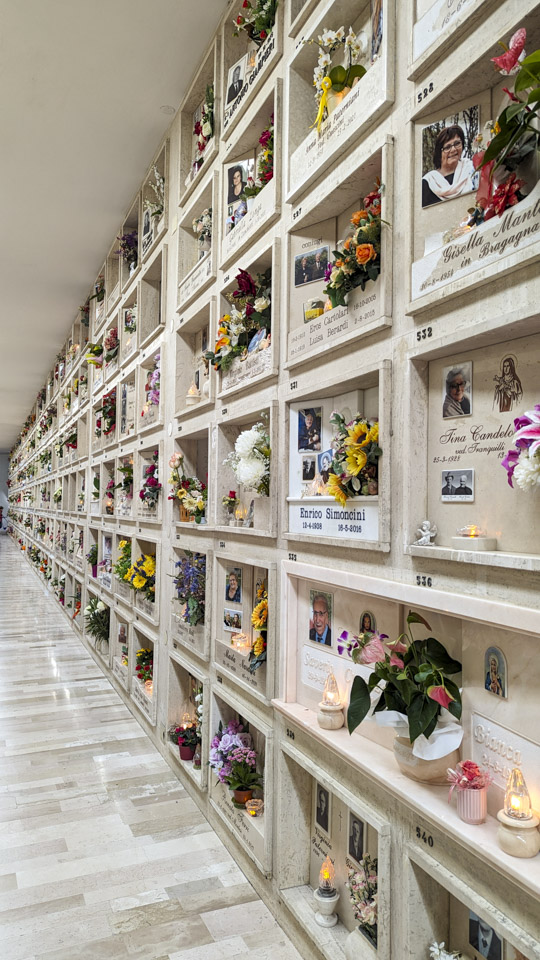 Looking down a long wall that had many spots to house the deceased. Almost all the spots have fresh cut flowers.