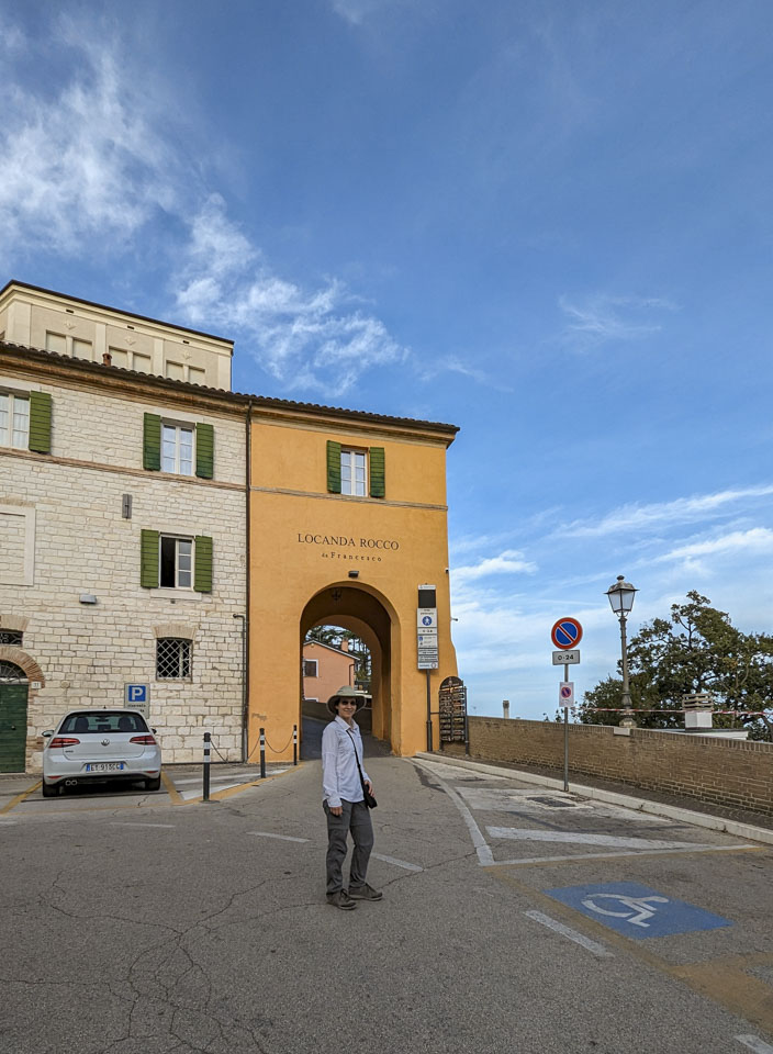 Anne is standing in front of a narrow archway where cars can enter the old historic city center.