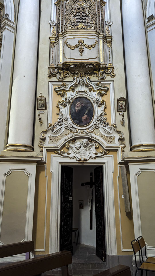 An open door inside the church with a portrait of a saint above it.