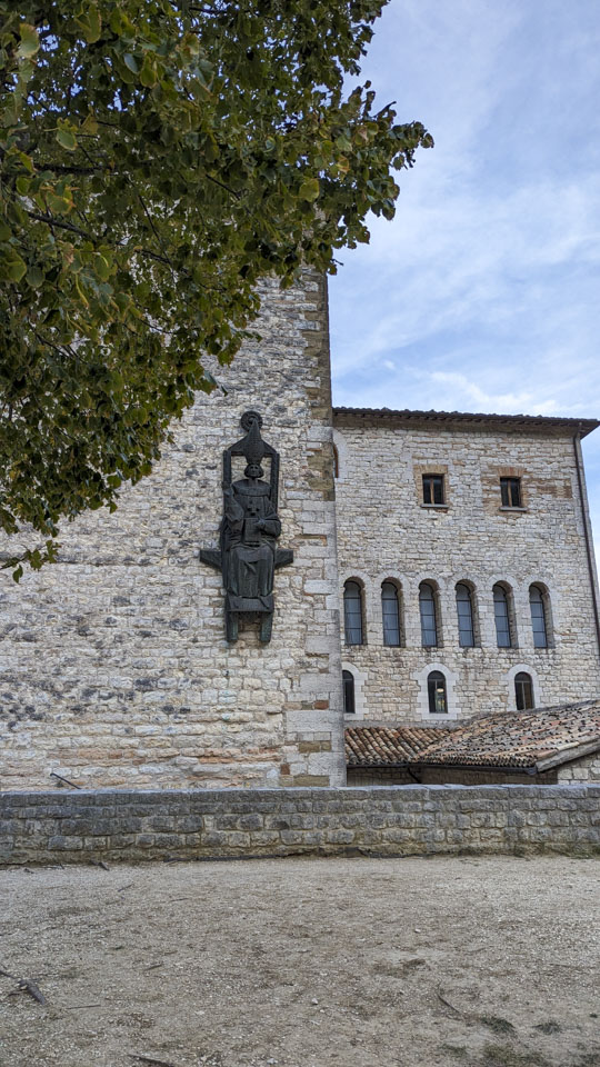 statue of a saint on the Fonte Avellana exterior wall