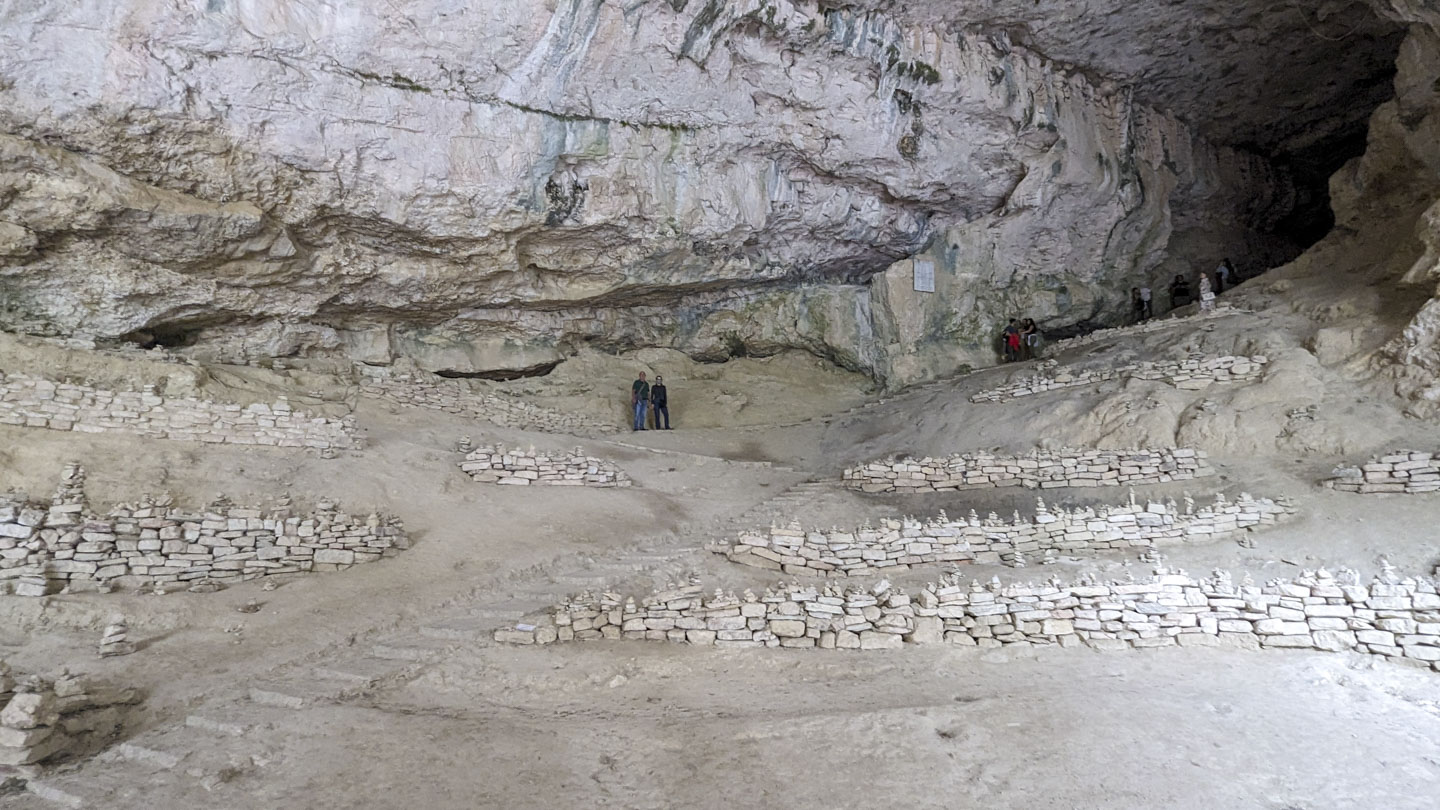 A view further into the cave behind the temple, showing a wide area with rock walls and steps.