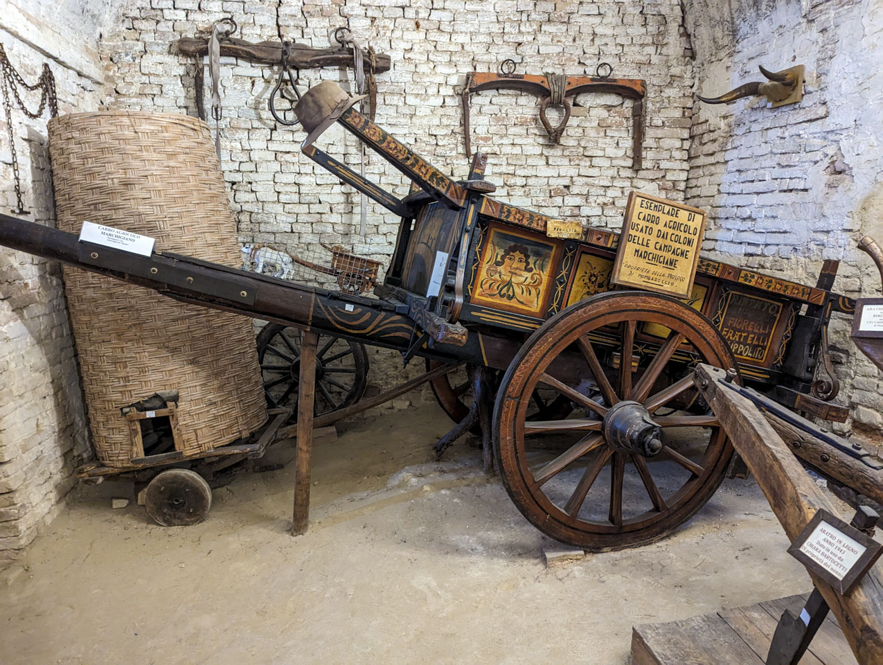 An attractive looking carriage with decorative painting on the sides. On the walls are also ox bows.