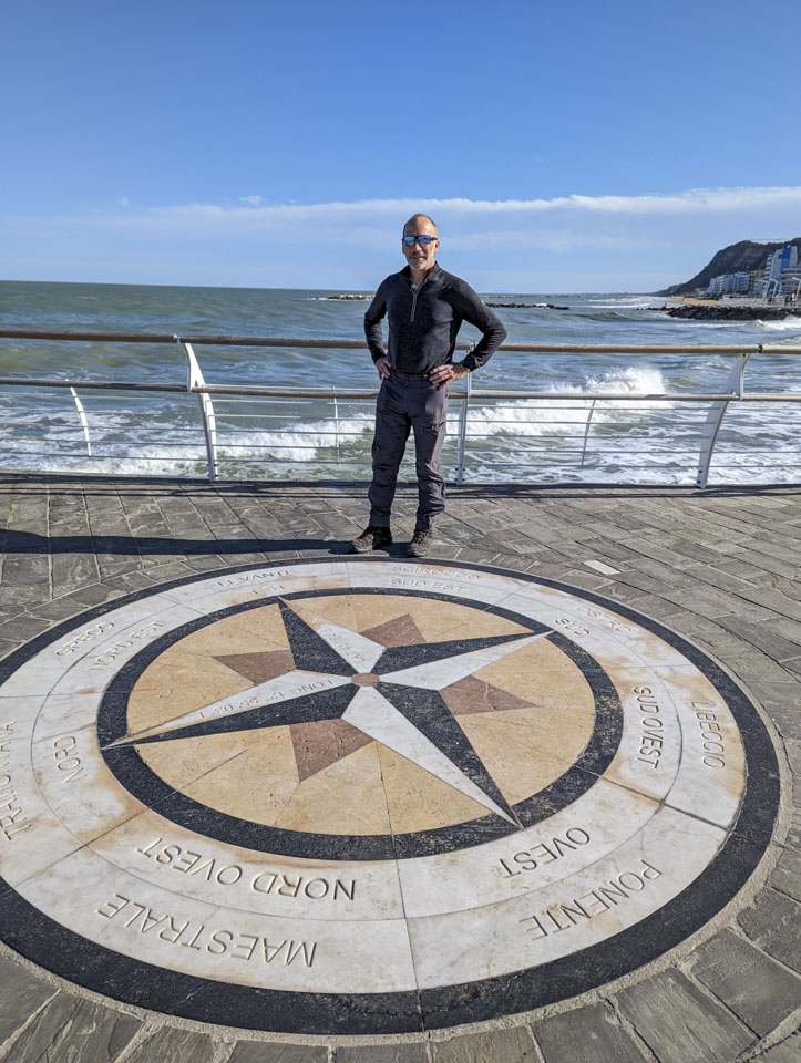 Paul standing next to a spot in the pavement where a compass has been made with colored bricks.