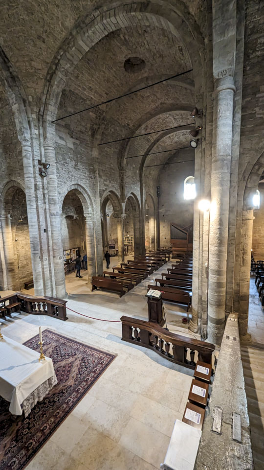 Take from an elevated height, this picture looks back down the church. Pillars on each side support a very high ceiling.
