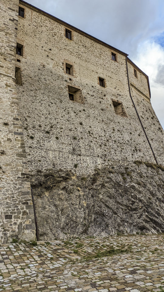 The fort rises many stories above the plaza. The bottom part of the fort is stone on the left but raw bedrock on the right.