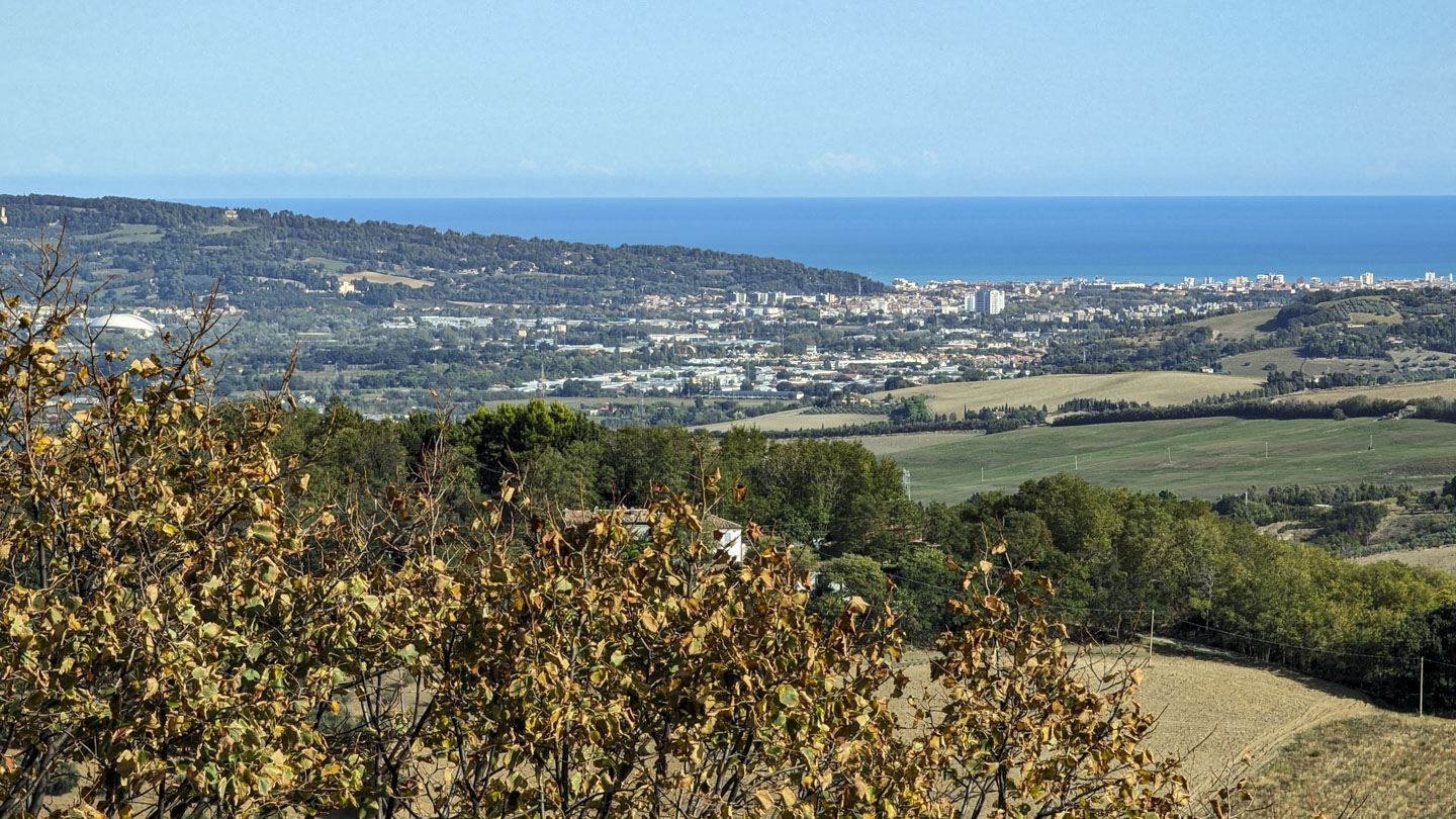 A city in the distance, with a hill on the left of the photo and the sea in the distance.