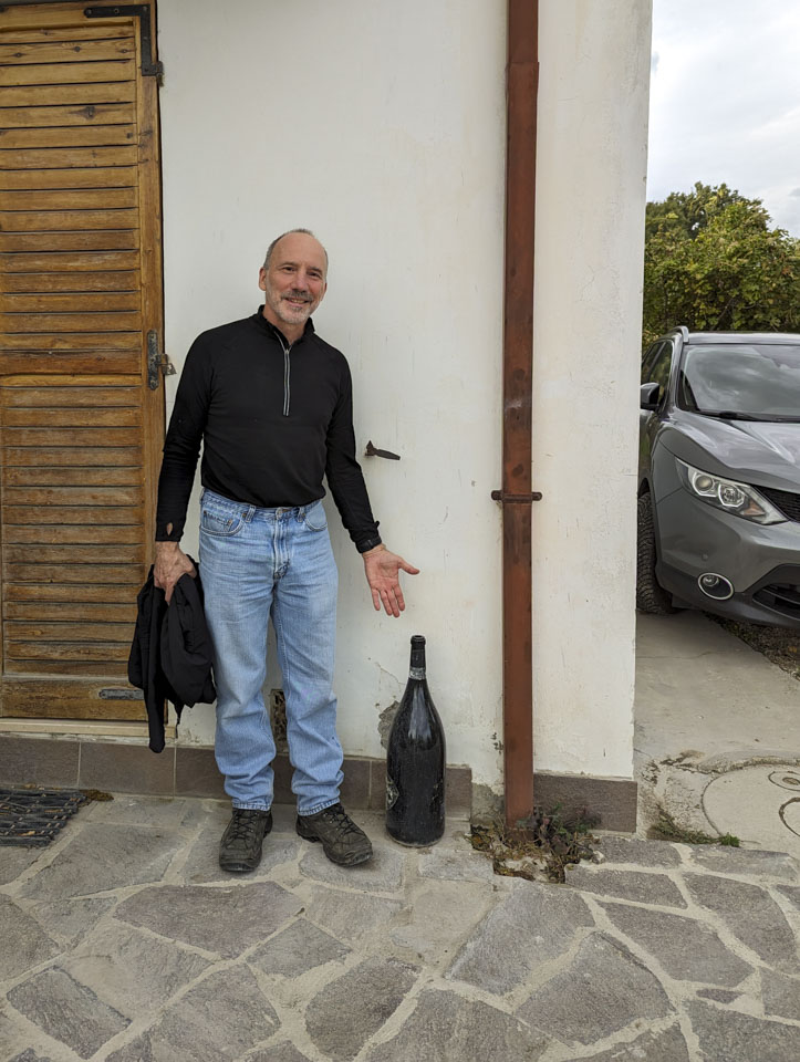 Paul standing next to an empty oversized wine bottle