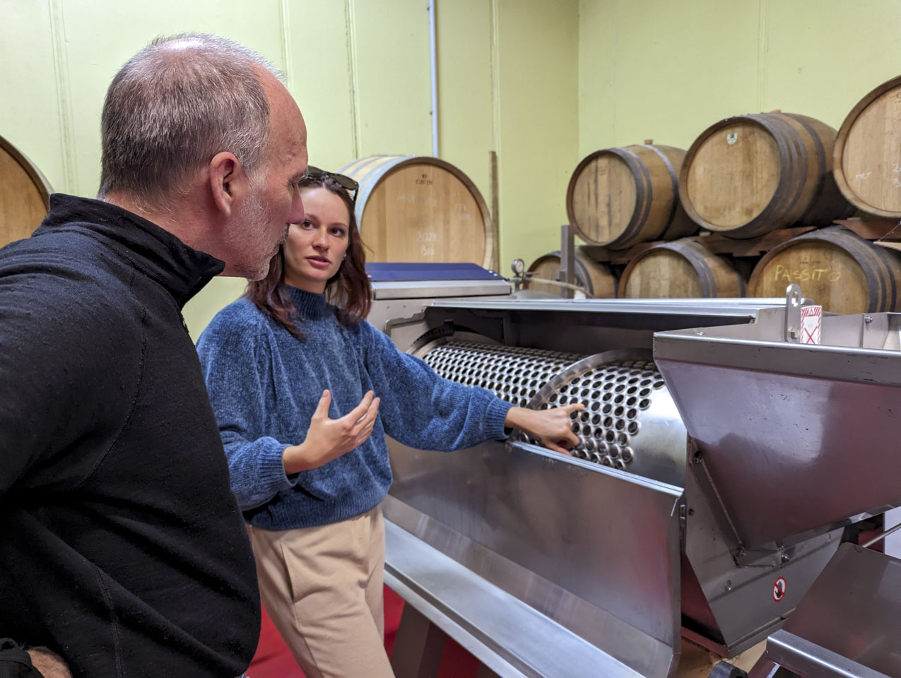 our tour guide standing in front of a stainless steel machine, with Paul listening