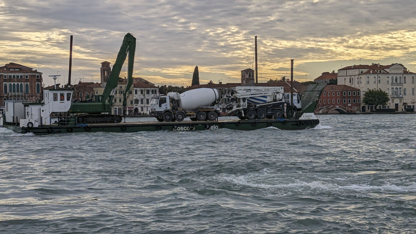 A crane and some cement trucks on a barge