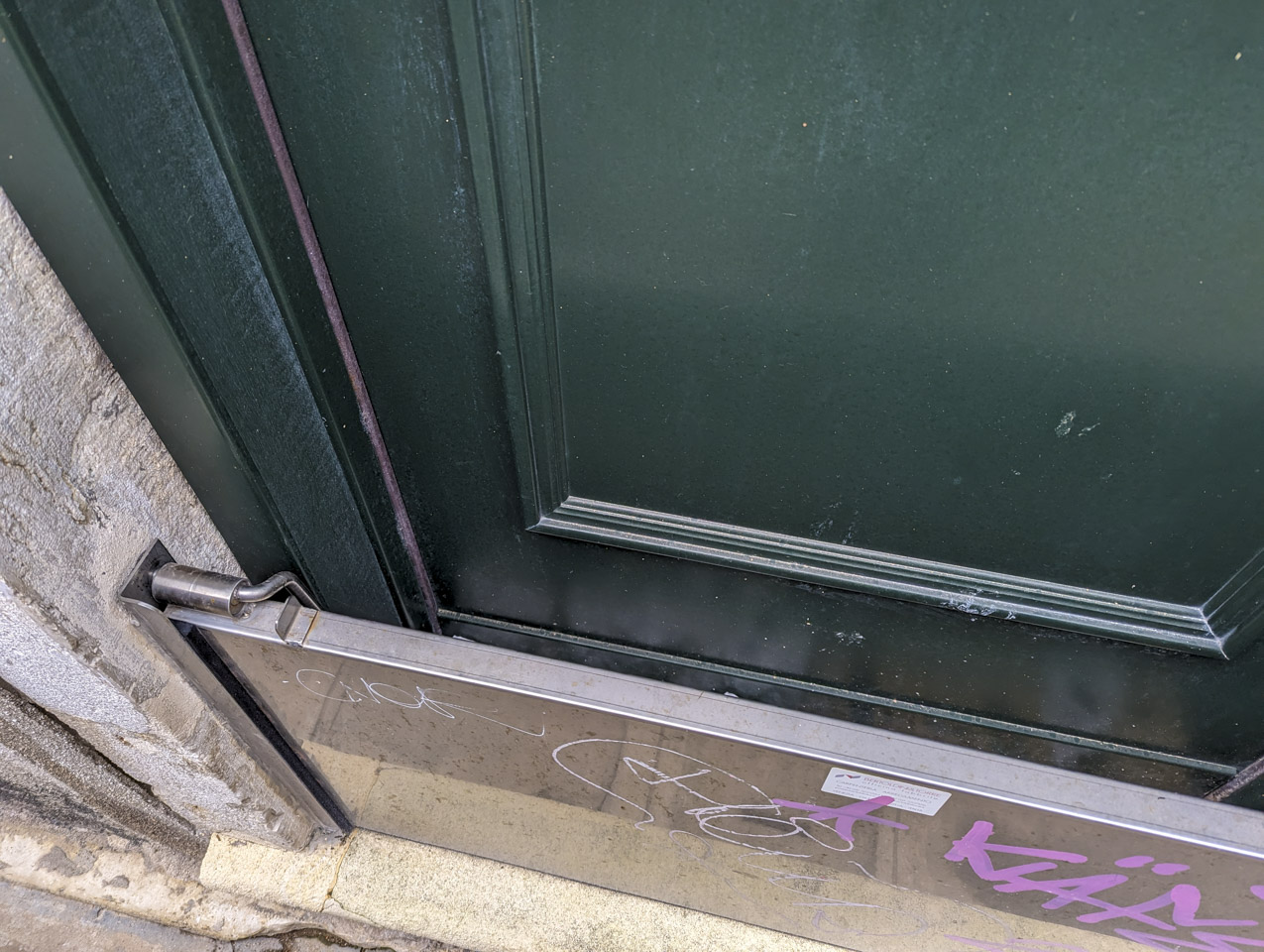 Looking down at the space between the metal plate and the green door