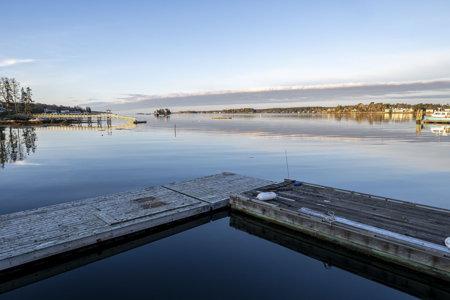Two piers meet at an angle in the foreground, with water continuing beyond into a harbor.