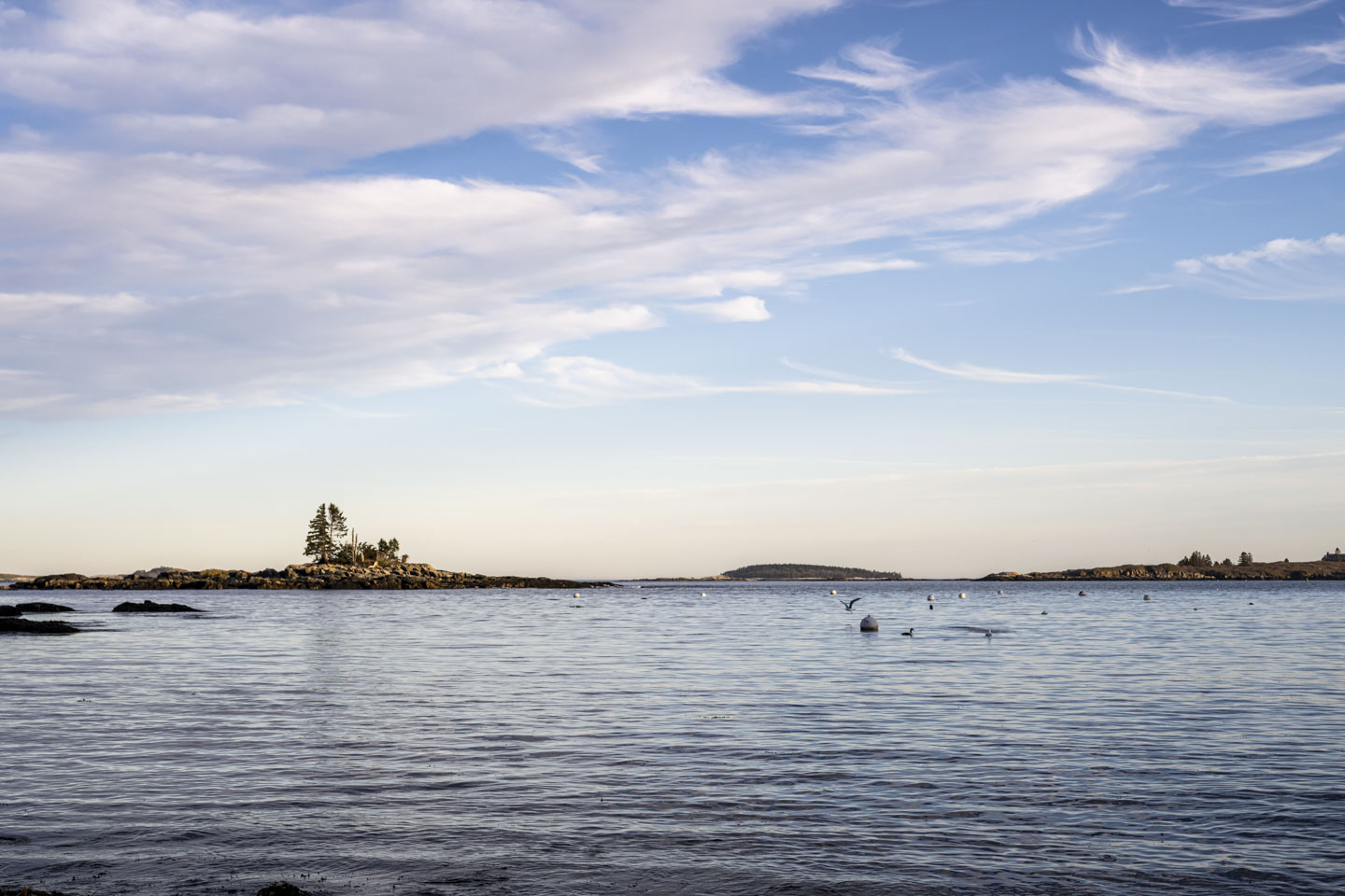 Water below, blue sky with white clouds above, and some islands in the middle.