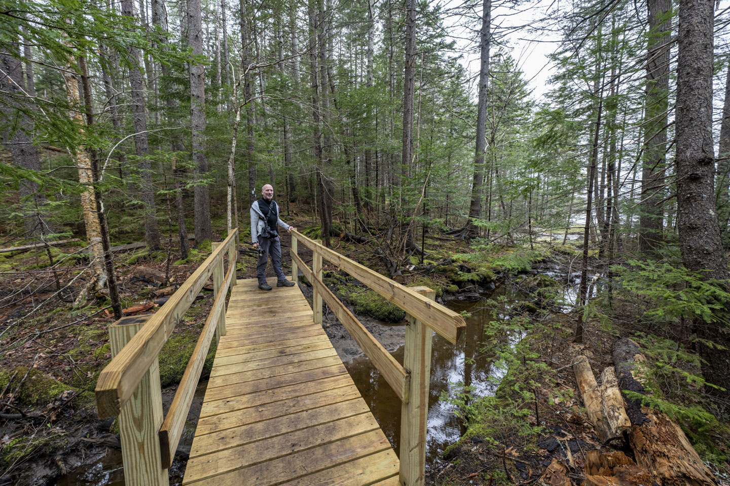 Paul is standing on a wooden bridge.