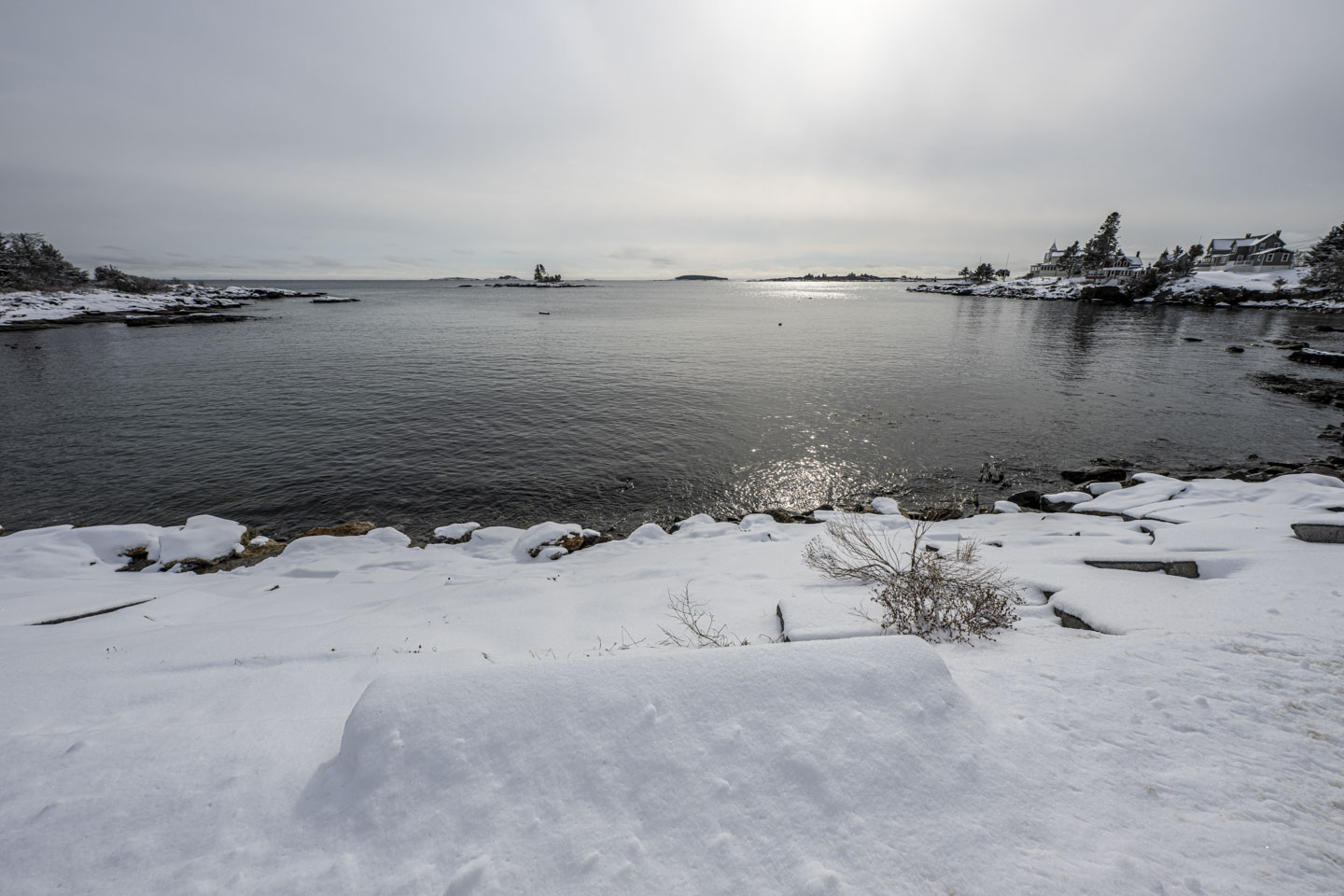 Snow in the foreground leads to calm water on a cloudy day.
