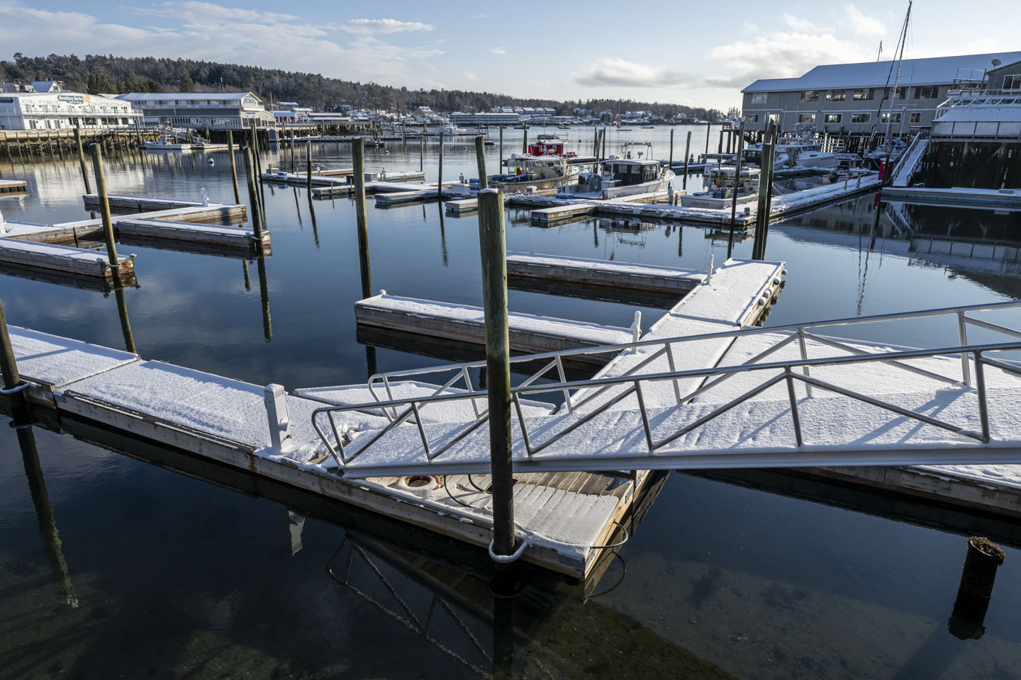 Empty boat slips have snow on them.