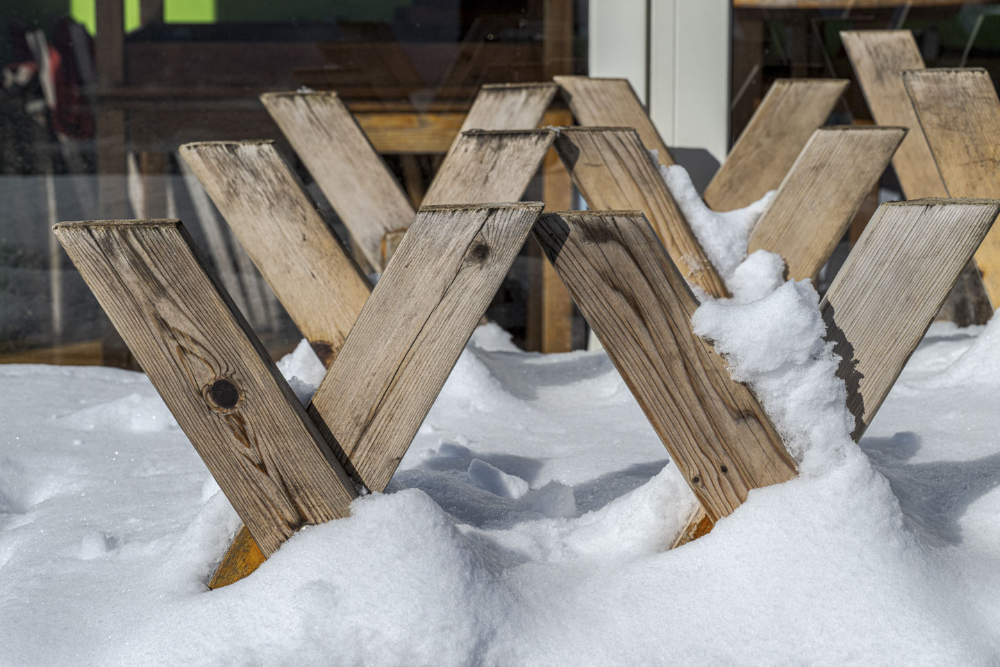 Outdoor picnic benches are upside down and covered with snow.