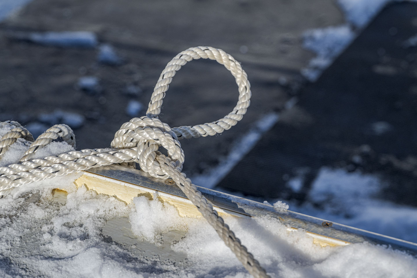 Some nautical rope is tied on a snowy dock.