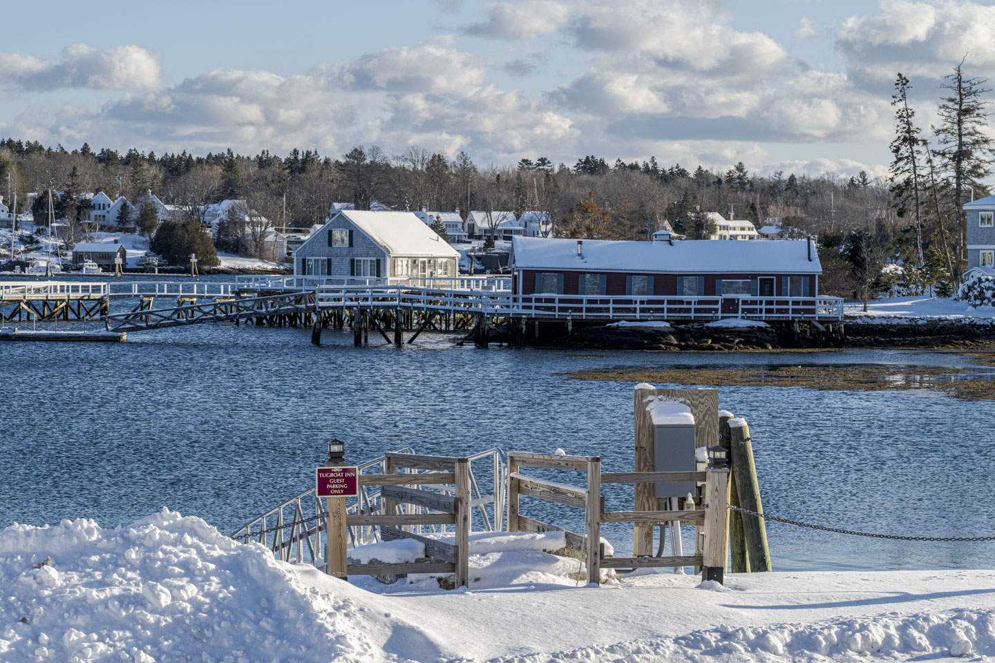 Snow blocks the entrance to a pier ramp, with a little red sign that states Tugboat Inn Guest Parking Only.
