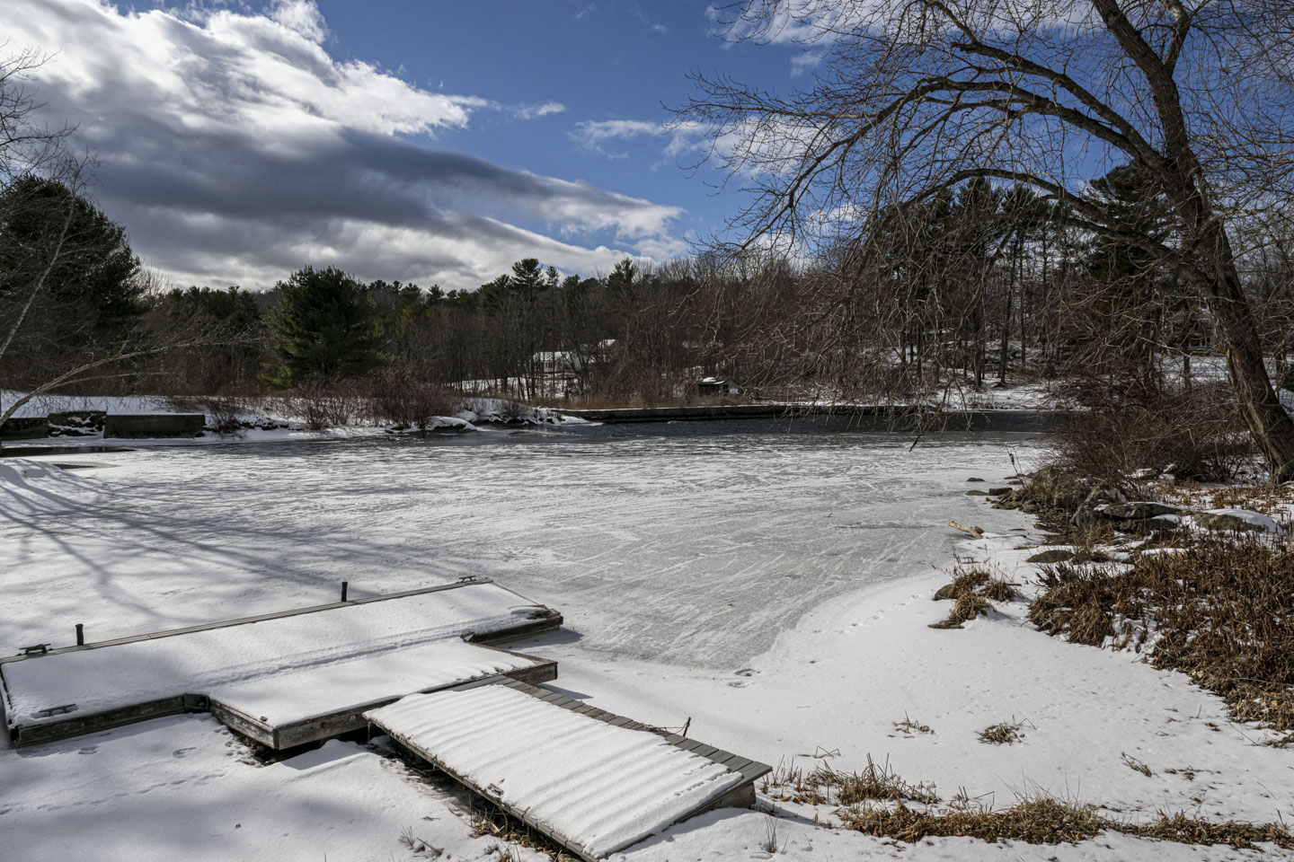 A small landing is covered with snow at the edge of an ice-covered river.
