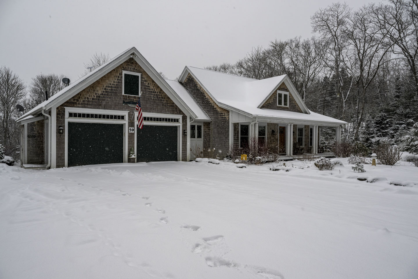 The front of the rental house. There is a 2-car garage on the left, and a porch in front of living area on the right.