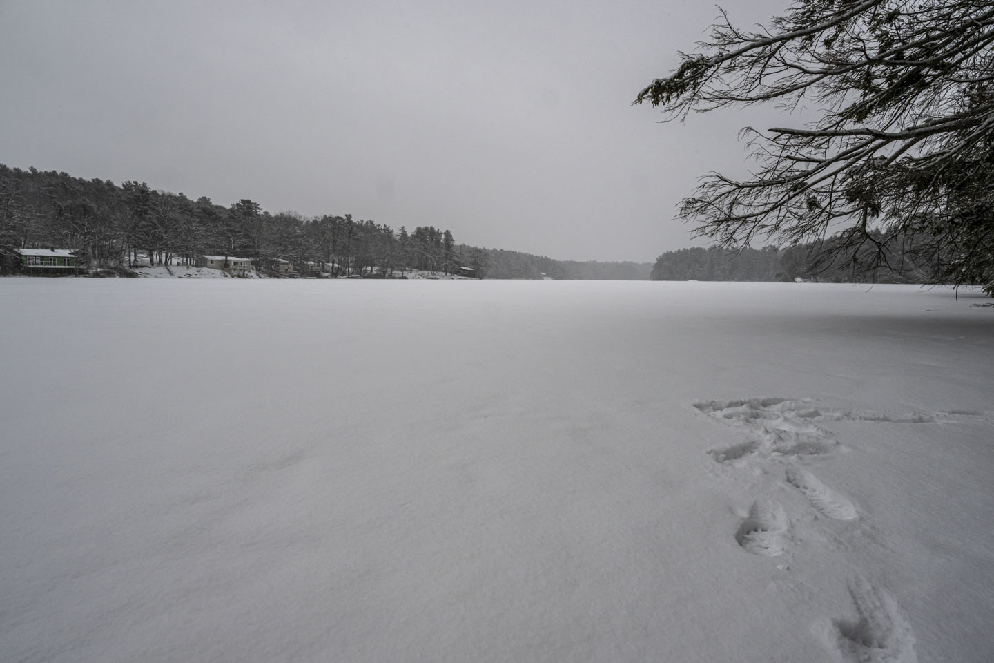 This picture shows the snow-covered lake. There are a few footprints close to us.