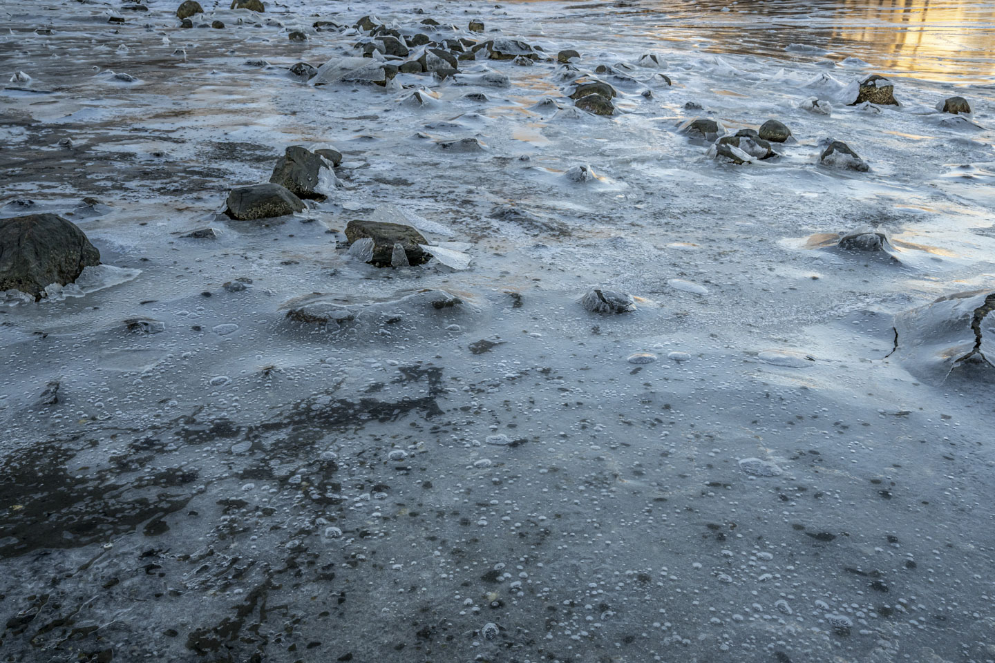 Rocks protrude through the ice, with broken shards at their sides.