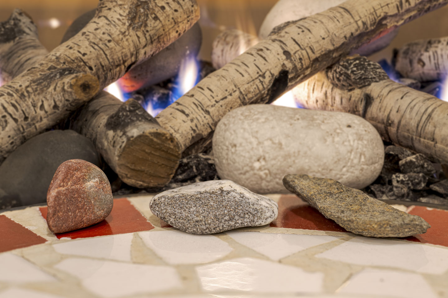 Three small rocks are in front of a fire.
