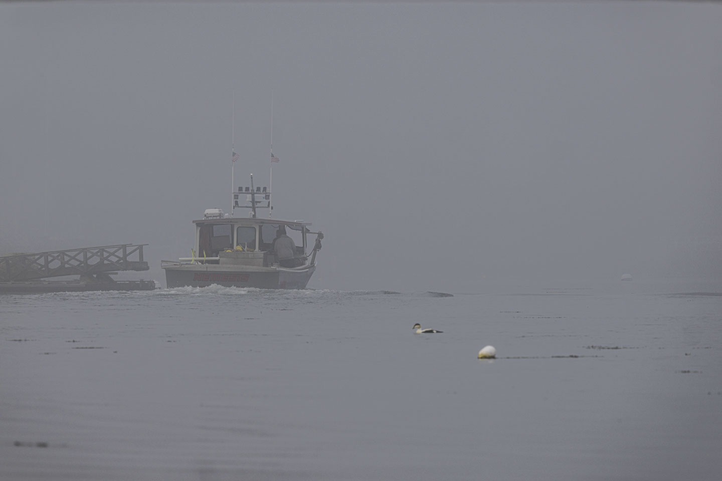 A boat leaves a pier and goes into the fog.