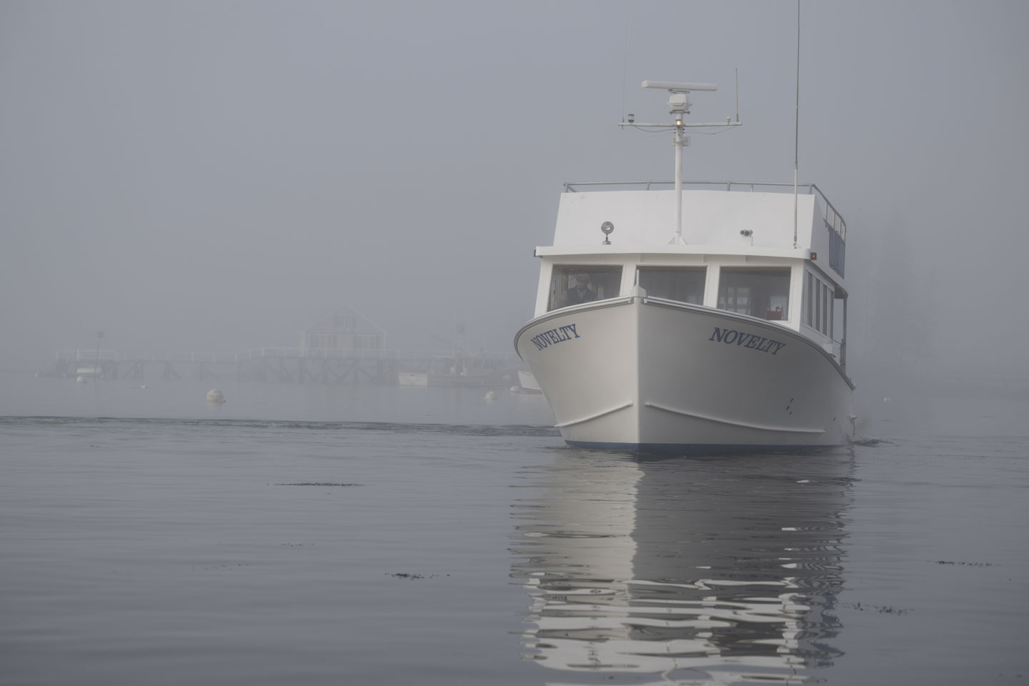 A passenger transportation boat comes towards us through the fog.