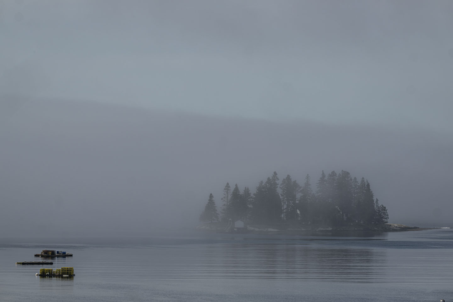 Blue water is in front of a fog-shrouded island.