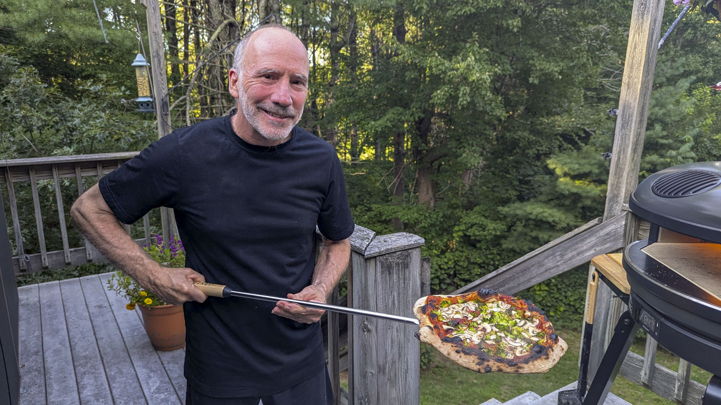 Paul holding a pizza on a peel.