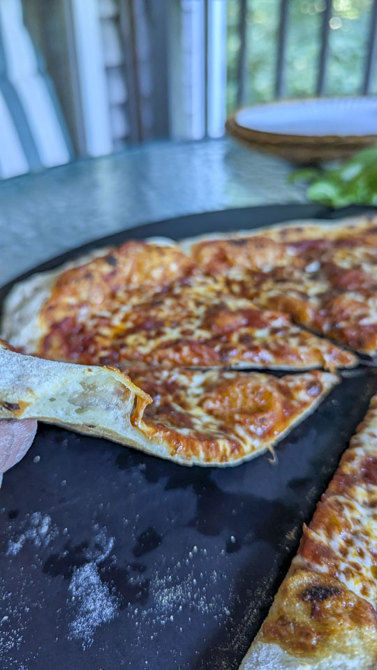 A close-up view of a thin crust pizza with a puffy outer crust.