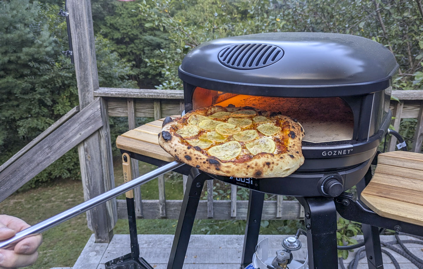The pizza is being pulled out from the pizza oven.