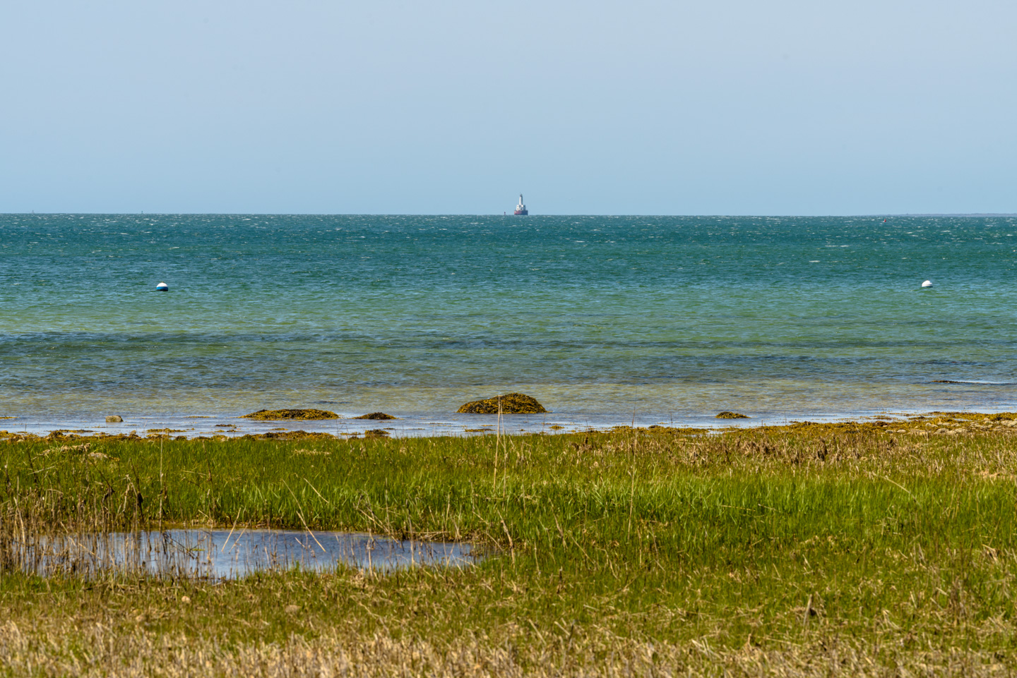 View out across the water with a lighthouse just showing in the distance
